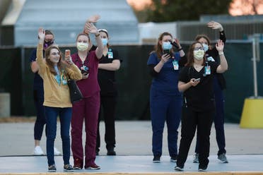 Hospital personnel wave and photograph people participating in a 