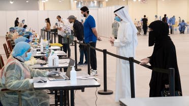 Kuwaitis, arriving from Europe, stand a safe distance apart to give their details to ministry of health officials in a makeshift coronavirus testing center. (File photo: Reuters)