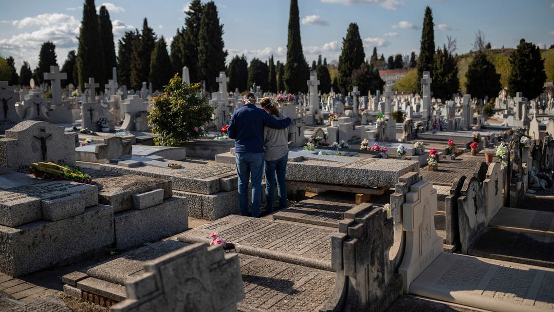 Two people attend a burial of a relative at a Madrid cemetery during the coronavirus outbreak in Madrid, Spain. (AP)