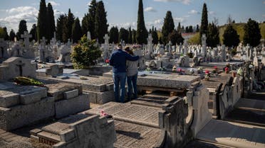 Two people attend a burial of a relative at a Madrid cemetery during the coronavirus outbreak in Madrid, Spain. (AP)