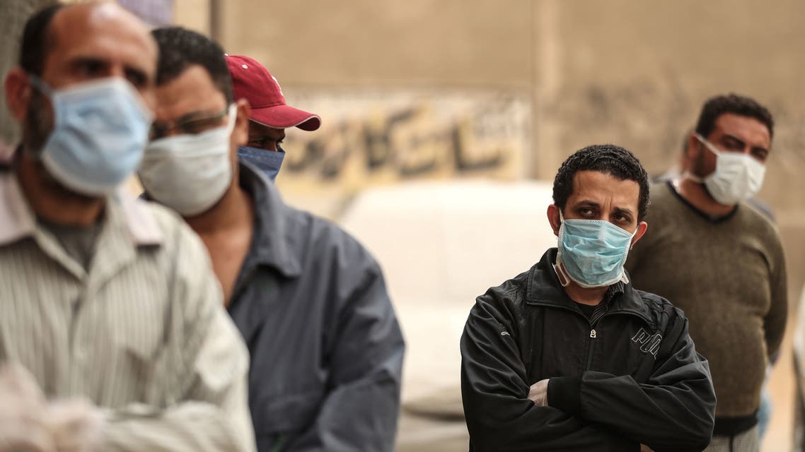 Egyptian men wearing masks wait outside a center of non-governmental organization Egyptian Food Bank to receive cartons with foodstuffs on April 05, 2020 in Cairo. (AFP)