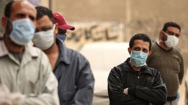 Egyptian men wearing masks wait outside a centre of non-governmental organisation Egyptian Food Bank to receive cartons with foodstuffs on April 05, 2020, as the charity distributes aid to people who lost their jobs due to the coronavirus pandemic crisis, in the Egyptian capital Cairo.
