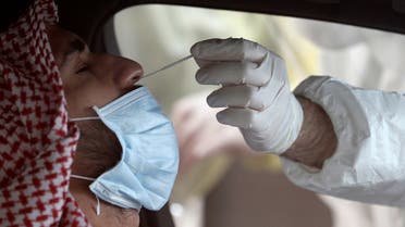 A member of medical staff wearing protective gloves takes a swab from a man during drive-thru coronavirus disease (COVID-19) testing at Bahrain Exhibition Center, in Manama, Bahrain. (Reuters)
