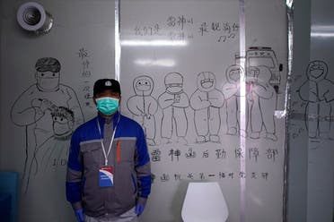 Security guard wearing a face mask stands in front of a sketch depicting medical workers inside the Leishenshan Hospital, a makeshift hospital for treating patients with the coronavirus disease (COVID-19), in Wuhan, Hubei. (Reuters)
