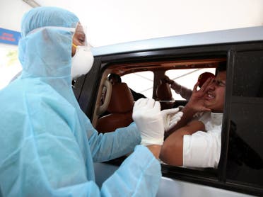 A member of medical staff wearing a protective face mask and gloves takes a swab from a man during drive-thru coronavirus disease (COVID-19) testing at Bahrain Exhibition Center, in Manama, Bahrain April 9, 2020. (Reuters)
