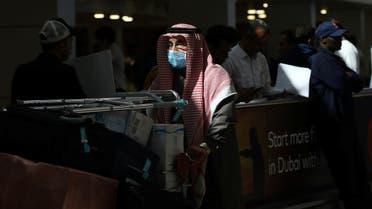 A traveller wears a mask as he pushes a cart with luggage at the Dubai International Airport, after the UAE's Ministry of Health and Community Prevention confirmed the country's first case of coronavirus. (Reuters)