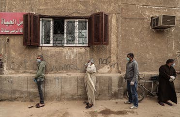 Egyptian men wearing masks wait outside a center of non-governmental organisation Egyptian Food Bank to receive cartons with foodstuffs. (File photo: AFP)