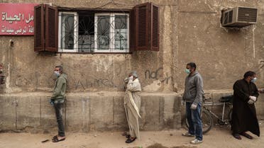 Egyptian men wearing masks wait outside a centre of non-governmental organisation Egyptian Food Bank to receive cartons with foodstuffs on April 05, 2020. (AFP)
