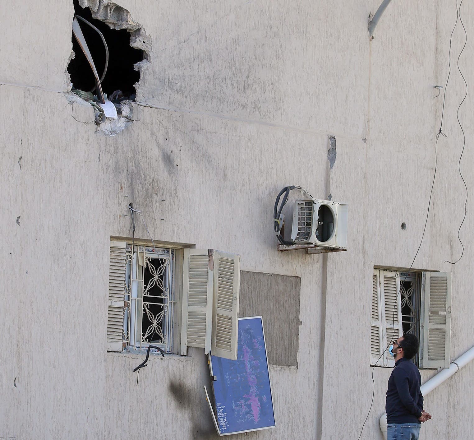 A man looks at a shrapnel hole in the wall of the Khadra General Hospital which is dedicated to treating people infected with coronavirus (COVID-19) in Tripoli on April 8, 2020. (AFP)