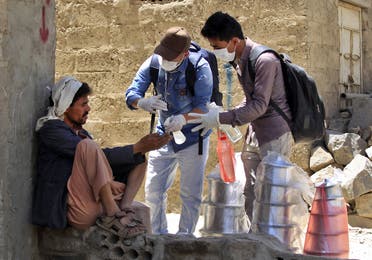 Yemeni volunteers spray disinfectant on the hands of a man in the one of Sanaa's impoverished neighborhoods, on March 30, 2020, amid concerns of a coronavirus outbreak. (AFP)