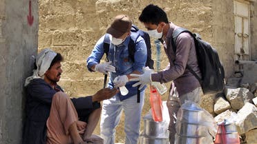 Yemeni volunteers spray disinfectant on the hands of a man in the one of Sanaa's impoverished neighbourhoods, on March 30, 2020, amid concerns of a coronavirus outbreak. (AFP)