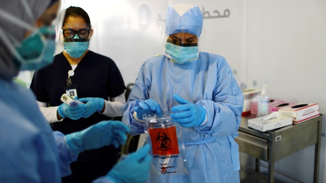 A member of medical staff wearing a protective face mask and gloves carries a swab tested during drive-thru coronavirus disease testing (COVID-19) at a screening centre in Abu Dhabi, United Arab Emirates, March 30, 2020. (Reuters)