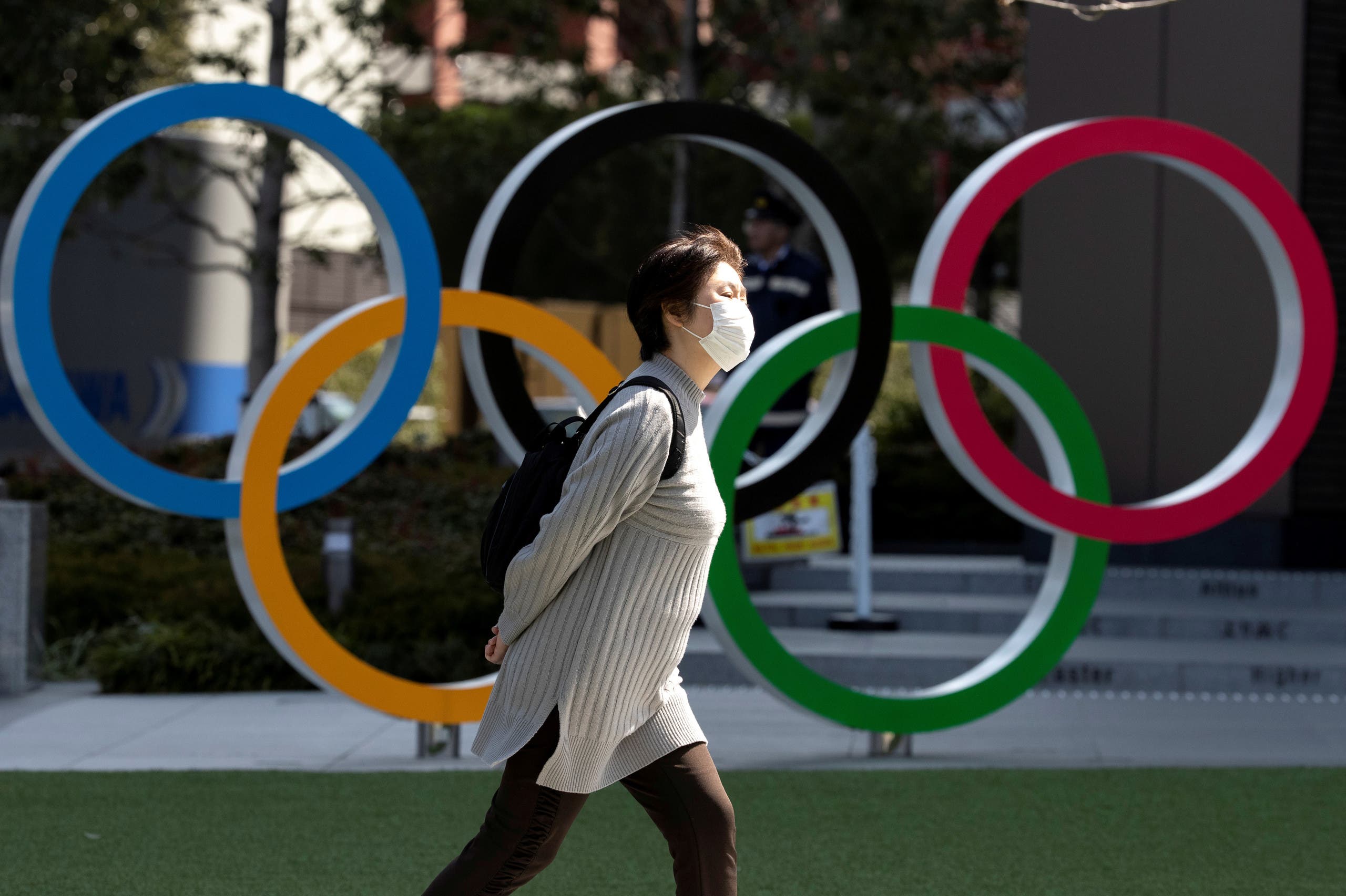 A woman wearing a protective face mask, following an outbreak of the coronavirus disease (COVID-19), walks past the Olympic rings in front of the Japan Olympics Museum in Tokyo, Japan March 13, 2020.  (Reuters)