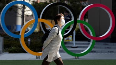 A woman wearing a protective face mask, following an outbreak of the coronavirus disease (COVID-19), walks past the Olympic rings in front of the Japan Olympics Museum in Tokyo, Japan March 13, 2020.  (Reuters)