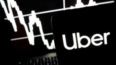 Logo of the Uber is seen on a smartphone screen as a picture of stock exchange graph is displayed on a computer screen in this illustration picture, May 7, 2019. (Reuters)