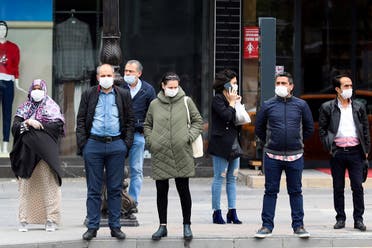 People wearing a facemask for protective measures wait to cross the street as the spread of the COVID-19, the novel coronavirus continues in Ankara. (AFP)