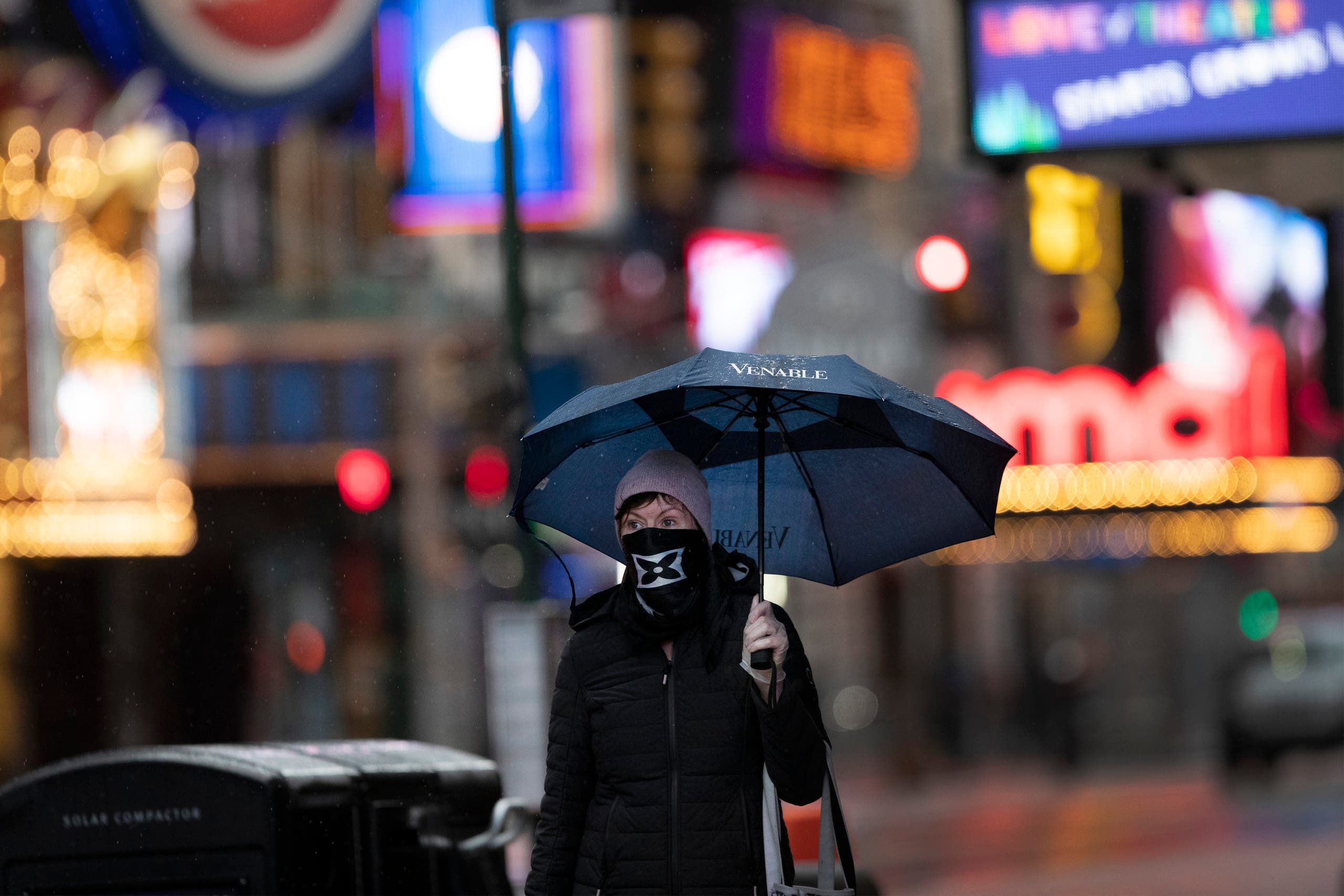 A woman wearing a mask and gloves walks through a rain storm in New York's Times Square on April 9, 2020, during the coronavirus epidemic. (AP)