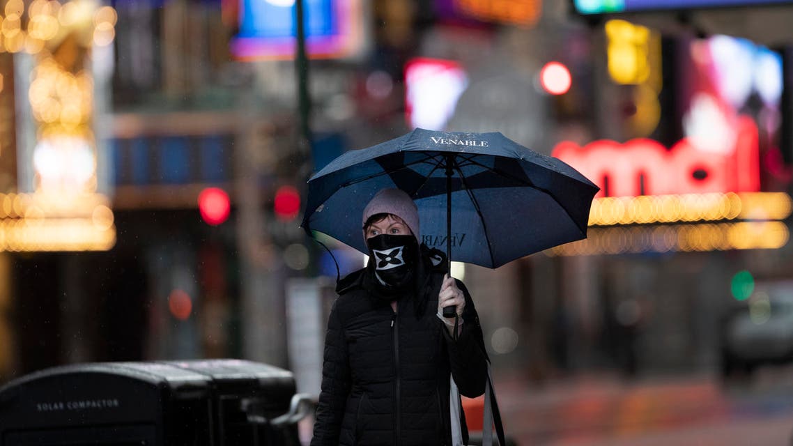  A woman wearing a mask and gloves walks through a rain storm in New York's Times Square on April 9, 2020, during the coronavirus epidemic. (AP)