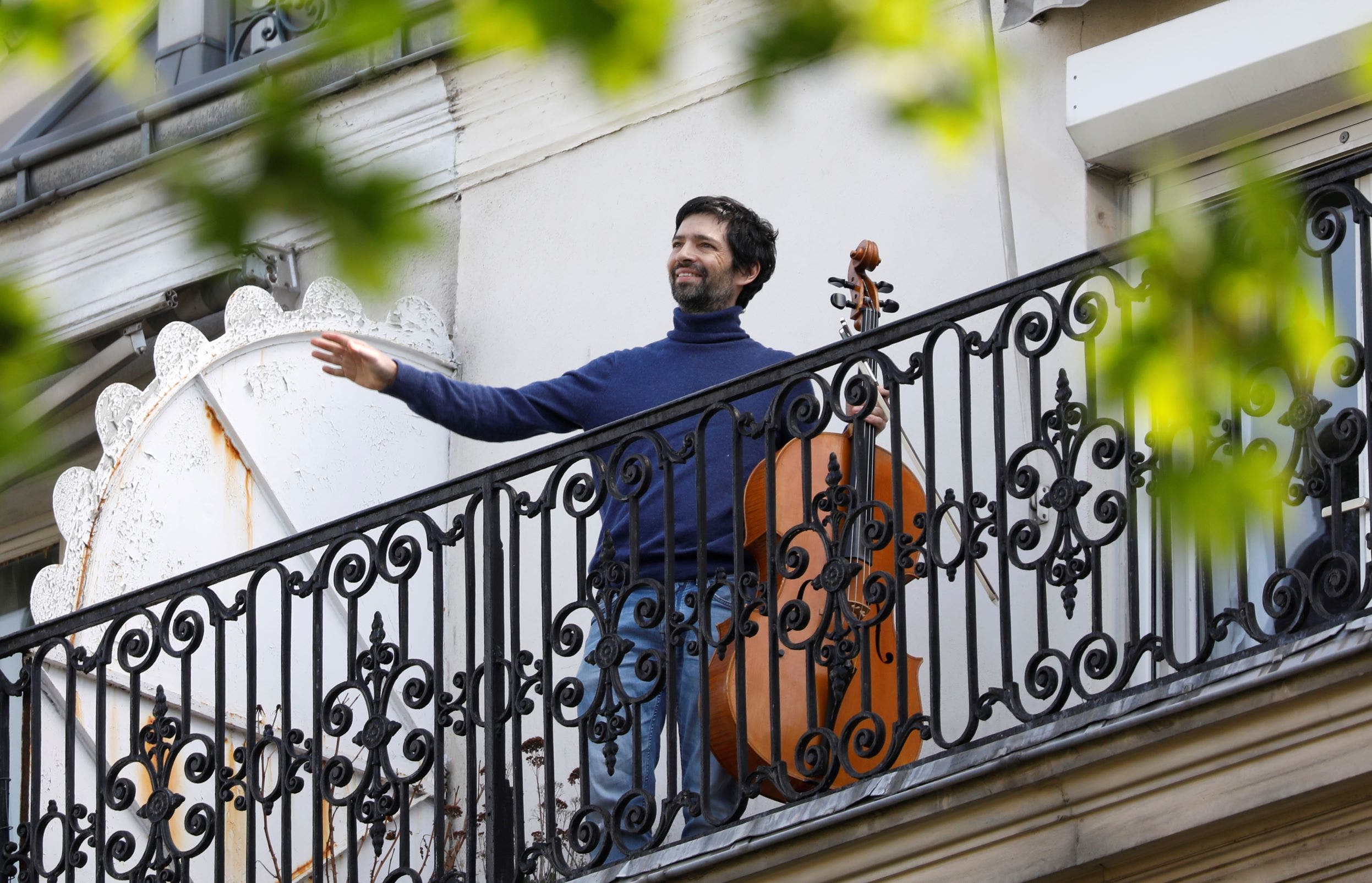 فرنسي يعزف من على شرفة منزله من باريس (رويترز)