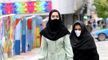 Iranians wearing protective mask walk past graffiti on a wall in Tehran on April 13, 2020 during the coronavirus COVID-19 pandemic. Iran's health ministry today reported another 111 deaths from the novel coronavirus, taking the official overall toll in the worst-hit Middle East country to 4,585. Ministry spokesman Kianoush Jahanpour said 1,617 new infections took the total number of cases in the country's outbreak to 73,303, of whom 45,983 had recovered.