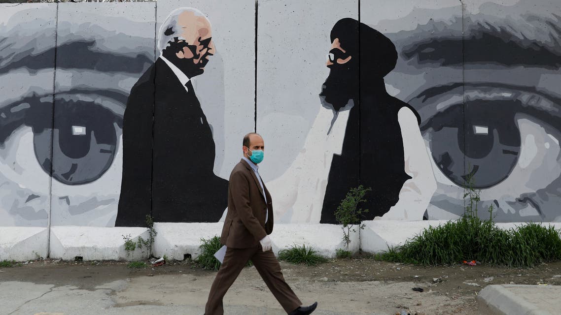 An Afghan man wearing a protective face mask walks past a wall painted with photo of Zalmay Khalilzad, U.S. envoy for peace in Afghanistan, and Mullah Abdul Ghani Baradar, the leader of the Taliban delegation, in Kabul, Afghanistan on April 13, 2020. (Reuters)