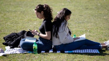 Letitia Klos, left, and her roommate Aesha Patel, both students at Boston University Dental School, spend time in The Public Garden in Boston, Friday, on March 27, 2020. (AP)