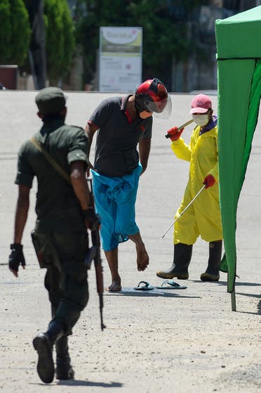 A municipal worker (R) sprays disinfectant solution on a man at a checkpoint during a government-imposed nationwide lockdown as a preventive measure against the spread of the COVID-19 coronavirus in Beruwala on April 16, 2020. (AFP)