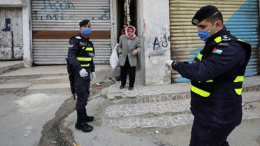Jordanian police officers stand guard as a man waits to get bread in a closed-down part of Al-Nasr area, amid the coronavirus disease (COVID-19) outbreak, in Amman, Jordan, April 15, 2020. REUTERS/Muhammad Hamed
