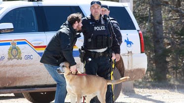RCMP officer Cedric Landry releases a dog to a man at the checkpoint onto Portapique Beach Road after Gabriel Wortman, a suspected shooter, was taken into custody in Portapique, Nova Scotia, Canada. (Reuters)