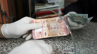 A customer wearing gloves holds Lebanese pounds at a currency exchange store in Beirut, April 3, 2020. (Reuters)