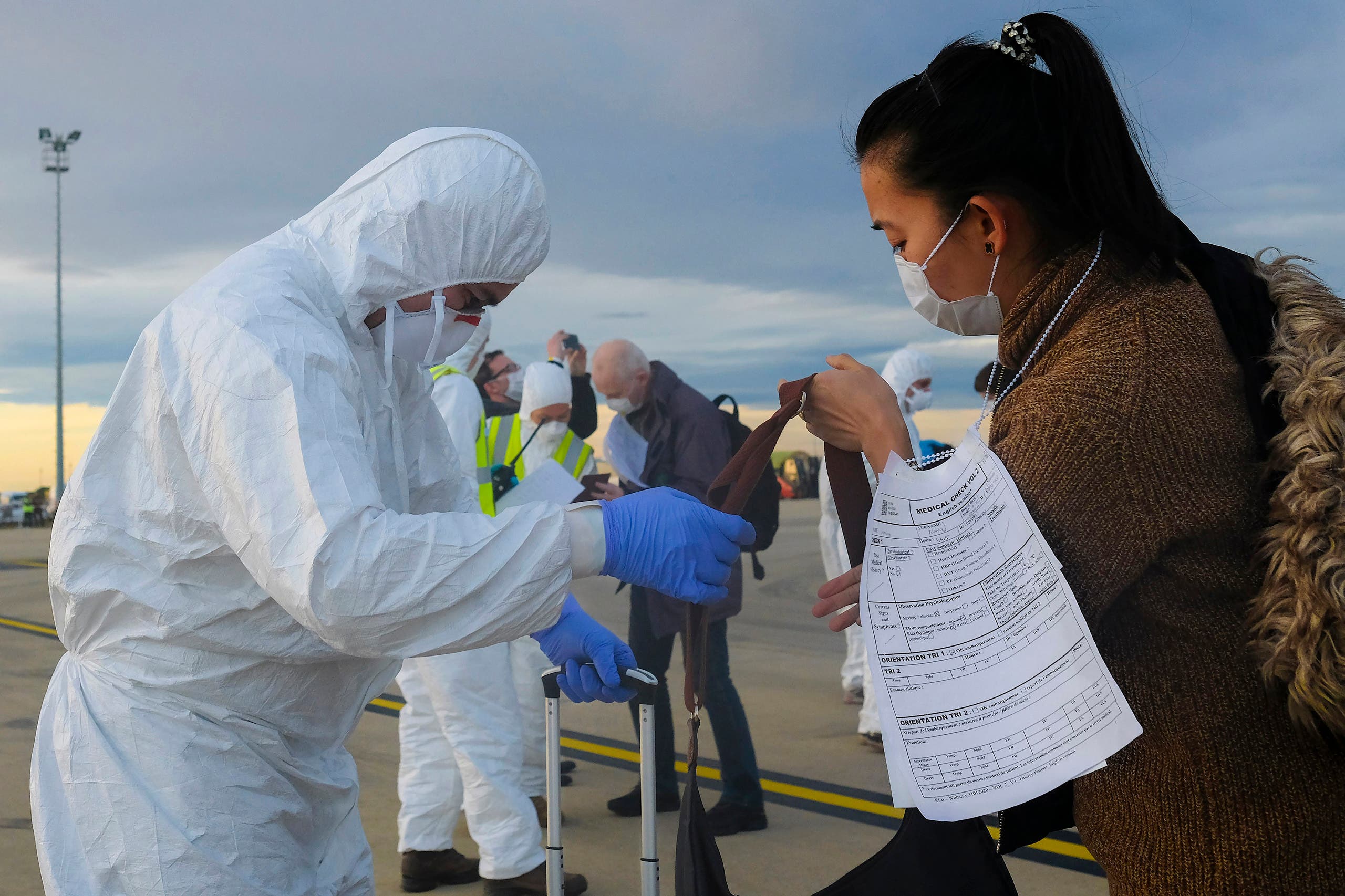 A worker wearing a protective suit checks the luggage of an evacuee from Wuhan, China, after their evacuation flight landed at an airport in Marseilles, France on Feb. 2, 2020. (AP)