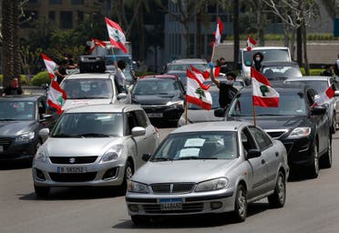 Anti-government protesters wave Lebanese flags from their cars as they protest by driving through the streets, in Beirut, Lebanon, on Tuesday, April 21, 2020. (AP)