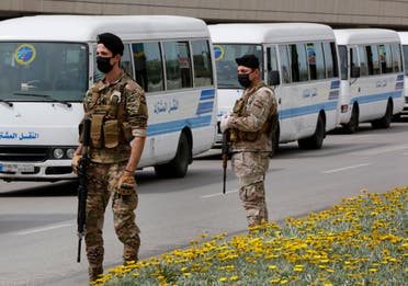 Lebanese army soldiers stand guard next to buses that will carry Lebanese passengers who were stuck in Saudi Arabia, at Rafik Hariri Airport, in Beirut on April 5, 2020. (AP)