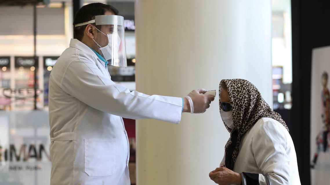 A man wears a face mask and a protective face shield as he checks a woman's temperature, to let her go inside the mall, following the outbreak of the coronavirus disease (COVID-19), after shopping malls and bazaars reopened in Tehran, Iran, April 20, 2020. WANA (West Asia News Agency)/Ali Khara via REUTERS ATTENTION EDITORS - THIS PICTURE WAS PROVIDED BY A THIRD PARTY?
