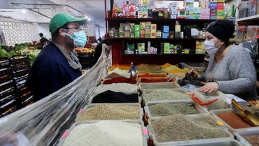 A vendor wearing a protective face mask serves a customer inside her shop, ahead of the Muslim holy month of Ramadan, amid concerns over the coronavirus disease (COVID-19), in Algiers, Algeria April 19, 2020. Picture taken April 19, 2020. REUTERS/Ramzi Boudina