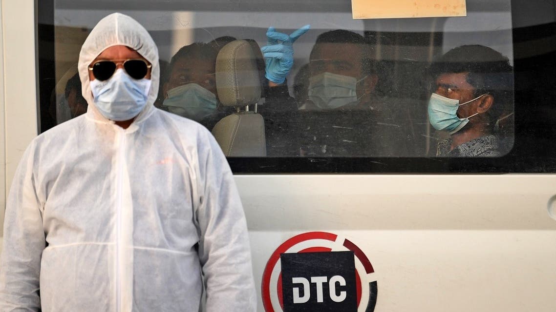 A health worker stands in front of a bus driving migrant workers who have been tested positive for the COVID-19 to the Warsan neighbourhood, where people infected or suspected of being infected by the virus are quarantined, in the Gulf Emirate of Dubai. (AFP)