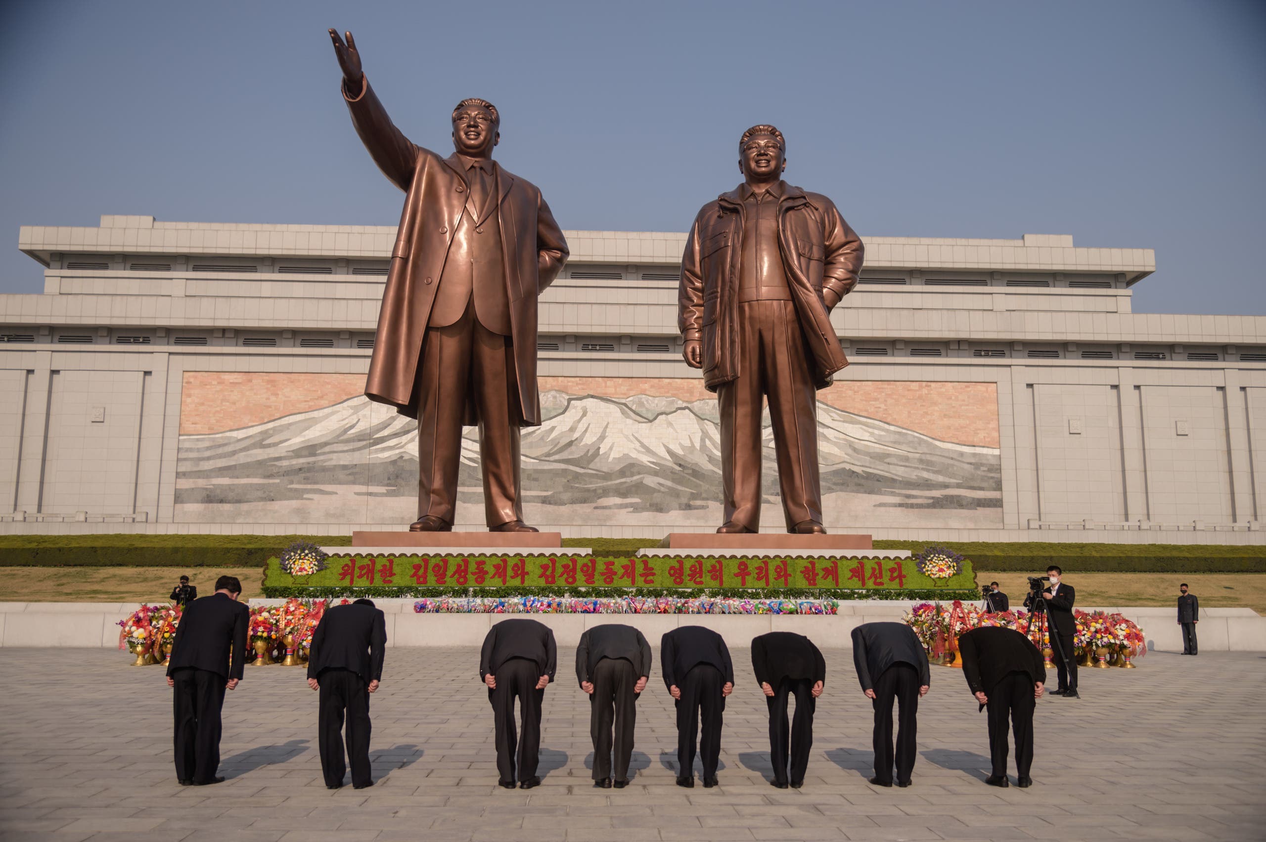 مواطنون من كوريا الشمالية ينحنون أمام تمثال للمؤسس وحفيده كيم يونغ أون (أرشيفية - فرانس برس)