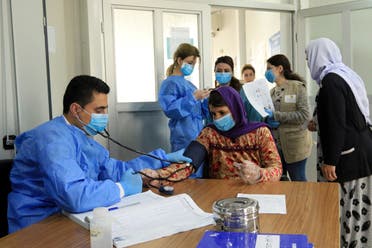 A doctor checks the blood pressure of a Yazidi displaced woman, as they wear protective face masks, following the coronavirus outbreak, at medical Center in the Sharya camp in Duhok, Iraq March 7, 2020. (Reuters)