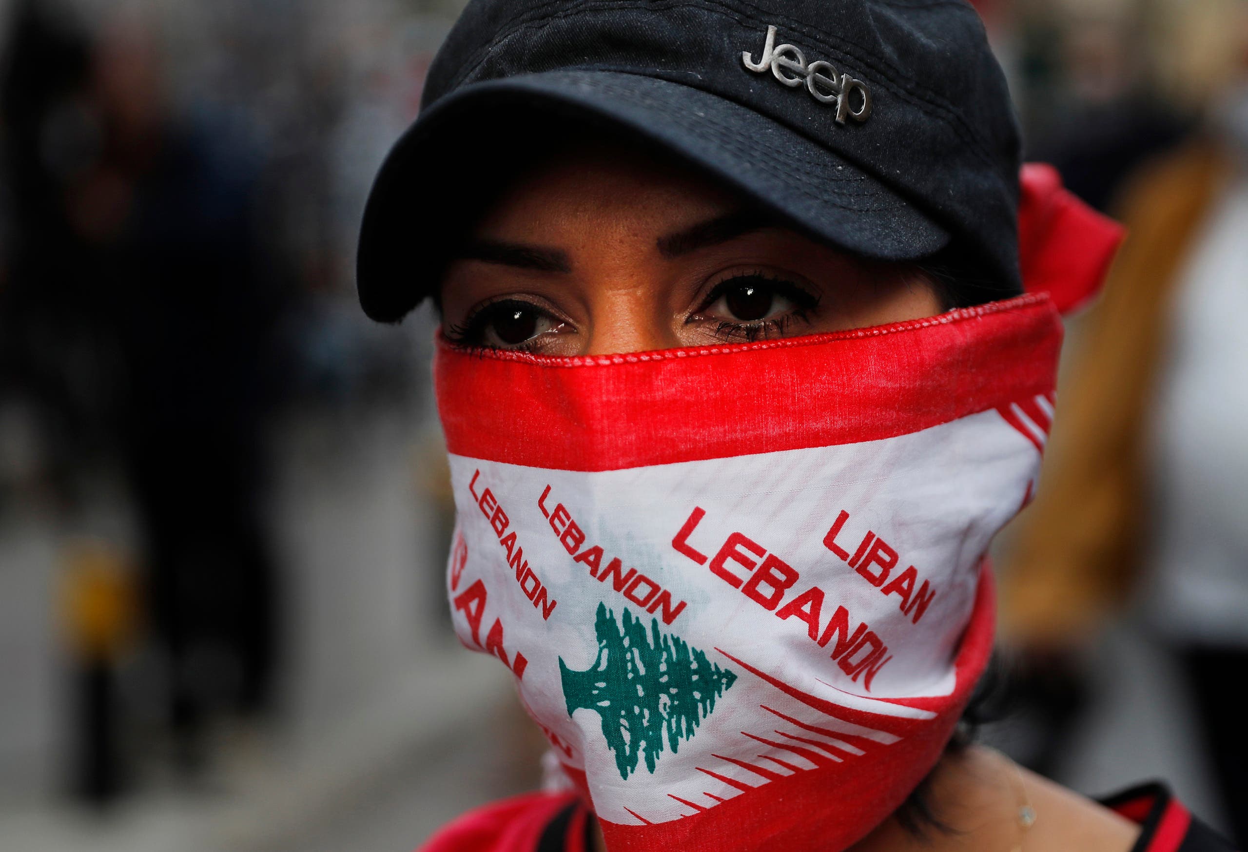 An anti-government protester covers her face with a Lebanese flag, using it as a mask to help curb the spread of the coronavirus, during a protest against the Lebanese central bank's governor and the deepening financial crisis in Beirut on April 23, 2020. (AP)