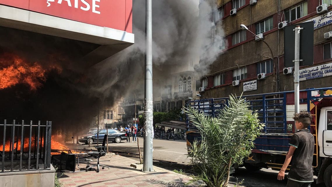 A boy looks on as the Banque Libano Francaise in central Tripoli burns. (Finbar Anderson)