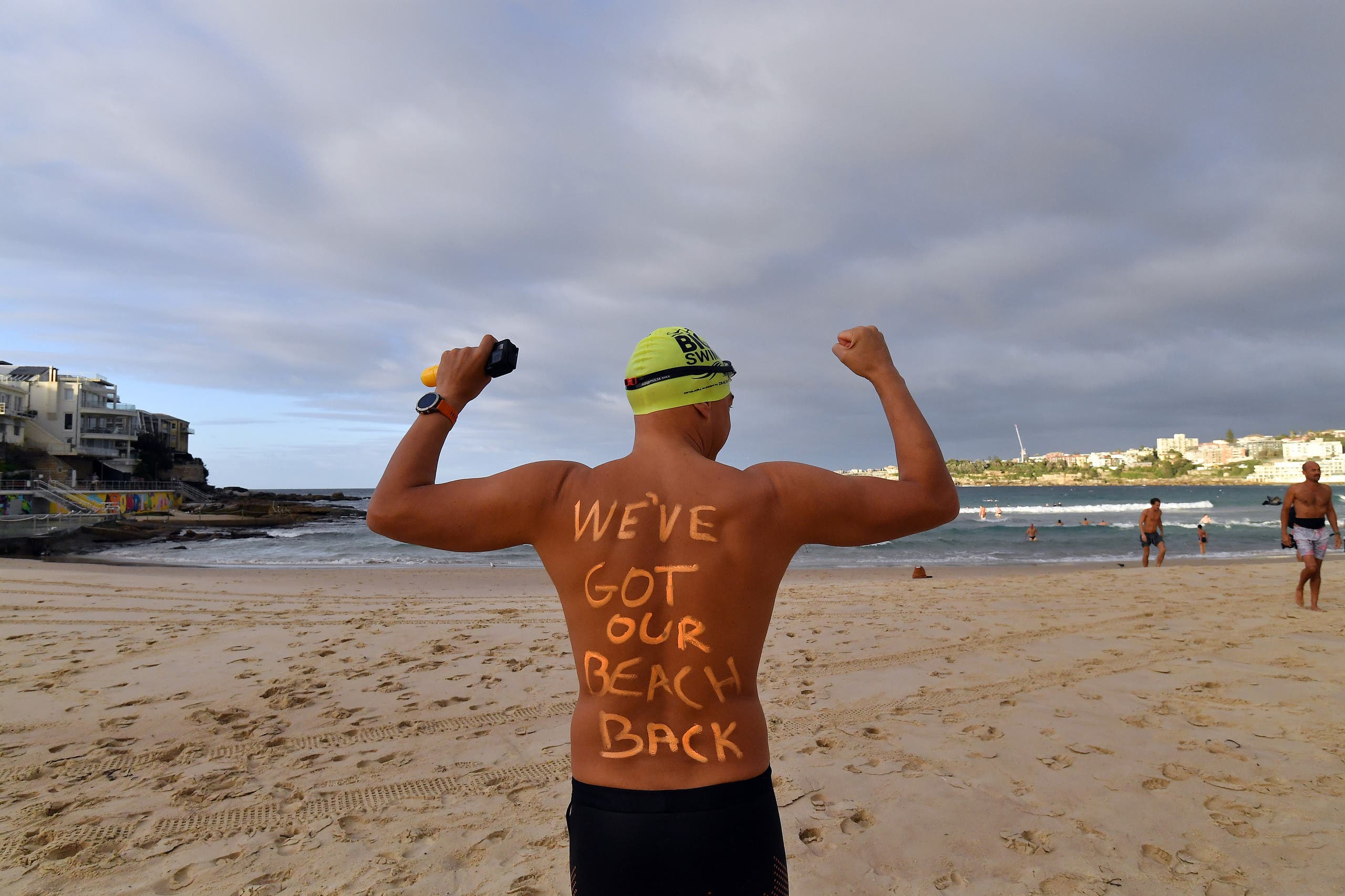 A man poses with a message on Bondi Beach. (AFP)