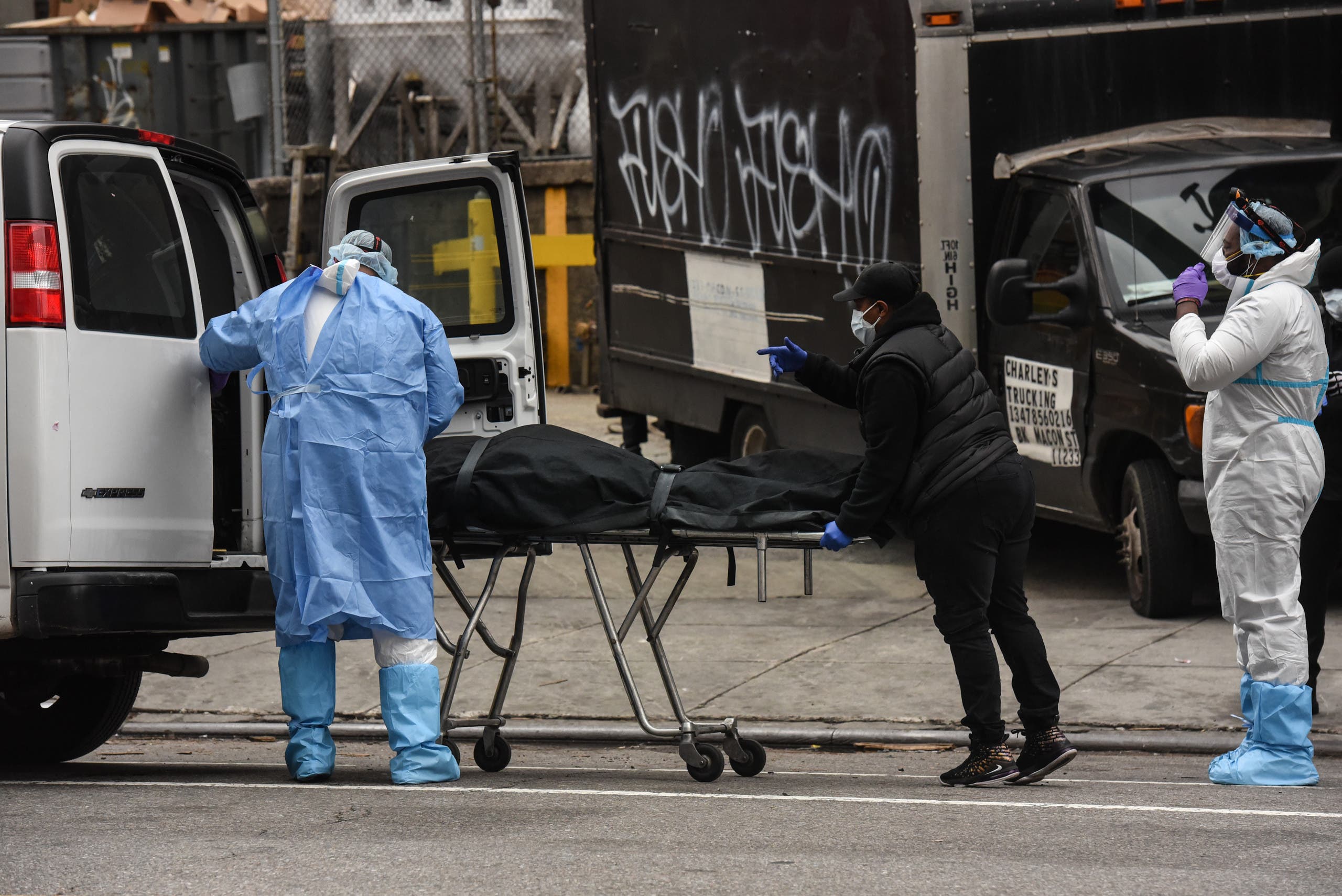 A funeral worker is assisted moving a deceased patient into a van at the Brooklyn Hospital Center on April 27, 2020 in the Brooklyn borough of New York City. (AFP)