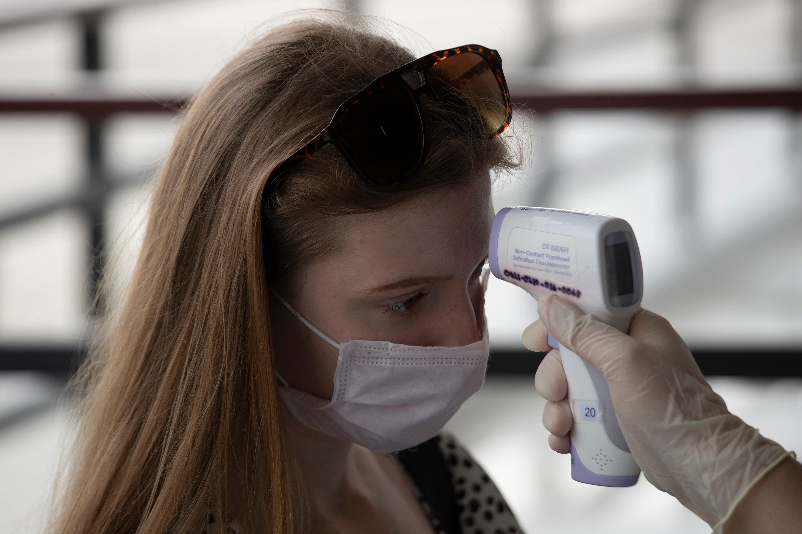 A health officer checks the temperature of a tourist who wants to extend visa at Immigration Bureau in Bangkok on March 27, 2020. (AP)