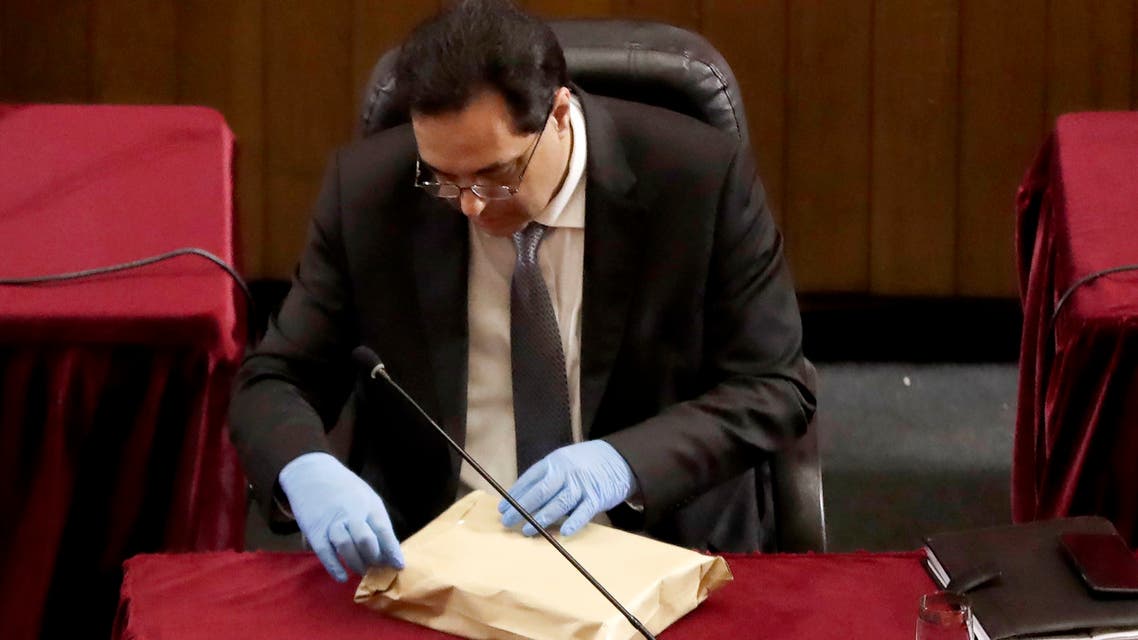 Lebanese Prime Minister Hassan Diab wearing gloves opens an envelope during a parliament meeting at the Unesco Palace in the capital Beirut, on April 21, 2020. Lebanon's parliament met in a conference hall to allow for social distancing between lawmakers amid the coronavirus pandemic, while outside anti-government protesters demonstrated in a car convoy. As the country struggles with a battered economy, MPs approved a $120 million loan from the World Bank to help fight COVID-19, which has officially infected 677 people and killed 21 nationwide.
