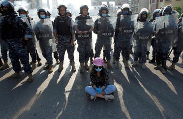 A demonstrator sits on the ground in front of Lebanese police officers during a protest against growing economic hardship in Beirut, Lebanon April 28, 2020. (Reuters)