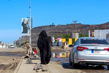 A woman begs for money, next to her children, from a vehicle in the southern Yemeni city of Aden on April 27, 2020, during the Muslim holy month of Ramadan. 