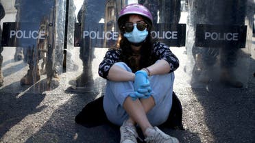 A Lebanese protester sits in front of riot police in the capital Beirut on April 28, 2020, as anger over a spiralling economic crisis re-energised a months-old anti-government movement in defiance of a coronavirus lockdown. Lebanese protesters confronted army troops for a second day as anger over a spiralling economic crisis re-energised a months-old anti-government movement in defiance of a coronavirus lockdown. Angered by the financial collapse, demonstrators have rallied across Lebanon, blocking roads and attacking banks, re-energising a protest movement launched in October against a political class the activists deem inept and corrupt. 