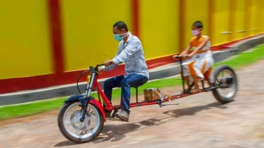 Self-made automobile engineer Partha Saha (L) tries his modified bike designed for social distancing as a preventive measure against the spread of the COVID-19 coronavirus with his daughter Pragya Saha in front of their house. (AFP)