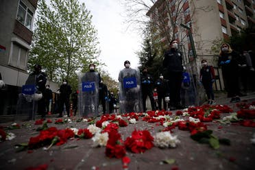 Turkish police officers, wearing face masks for protection against coronavirus, stand behind carnations left by demonstrators during May Day protests in Istanbul, on May 1, 2020. (AP)