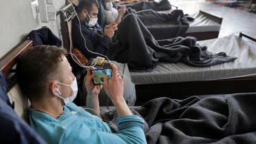 Men under quarantine wearing medical masks are seen playing video games in a quarantine site in Syria's northwest. (Reuters) 